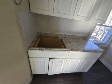 kitchen with white cabinets, light stone countertops, and sink