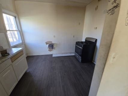 kitchen featuring white cabinets, black range with gas stovetop, and dark wood-type flooring