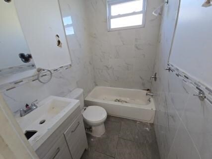 529 Communipaw Ave, Jersey City, NJ 07304 - full bathroom featuring vanity, shower / bathtub combination, and tile walls