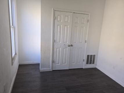 unfurnished bedroom with dark hardwood / wood-style flooring and a closet