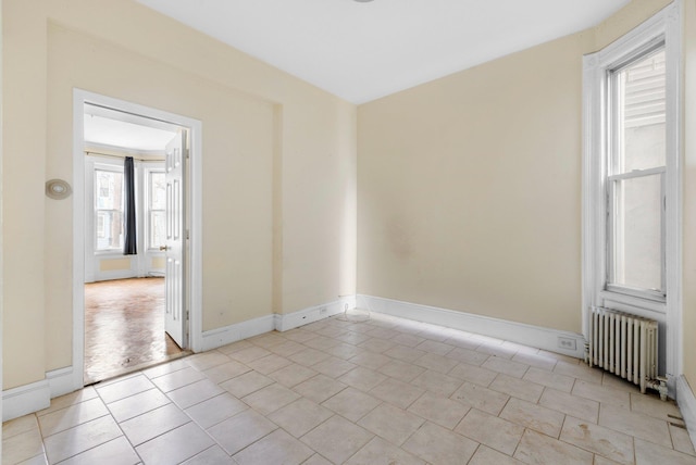 unfurnished room featuring light tile patterned flooring, radiator, and baseboards