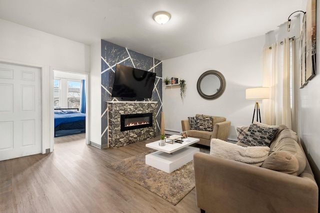 living room featuring a baseboard heating unit, baseboards, wood finished floors, and a fireplace