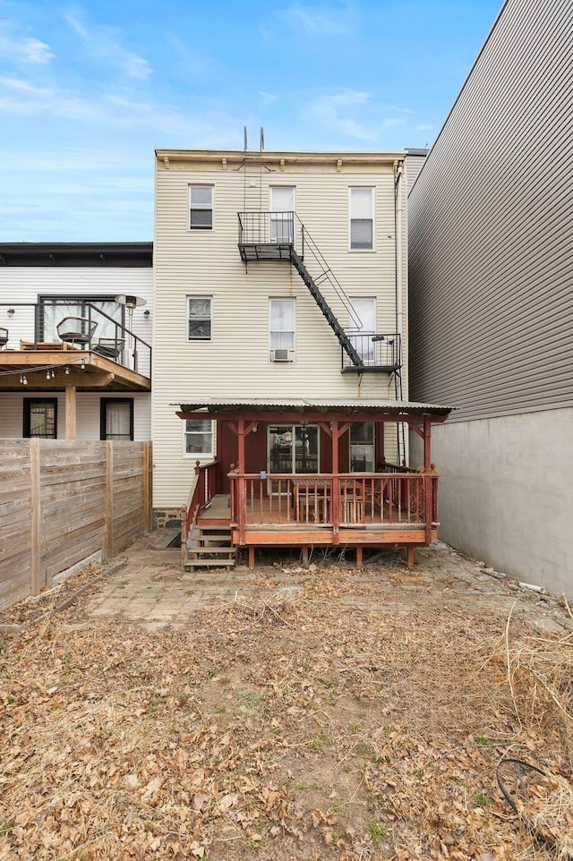 rear view of property featuring a deck, a balcony, and fence