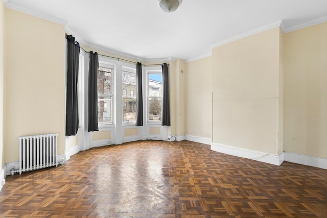 spare room featuring radiator, crown molding, and baseboards