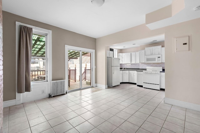 kitchen with white appliances, light tile patterned floors, electric panel, radiator heating unit, and tasteful backsplash