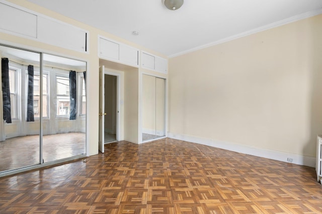 unfurnished bedroom with baseboards, multiple closets, and ornamental molding