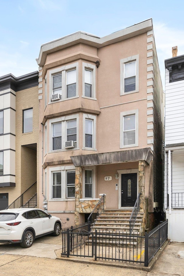 multi unit property featuring cooling unit, a fenced front yard, and stucco siding