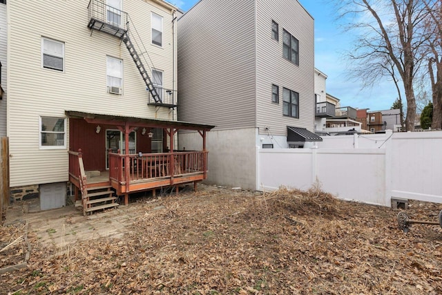 rear view of house featuring a deck and fence