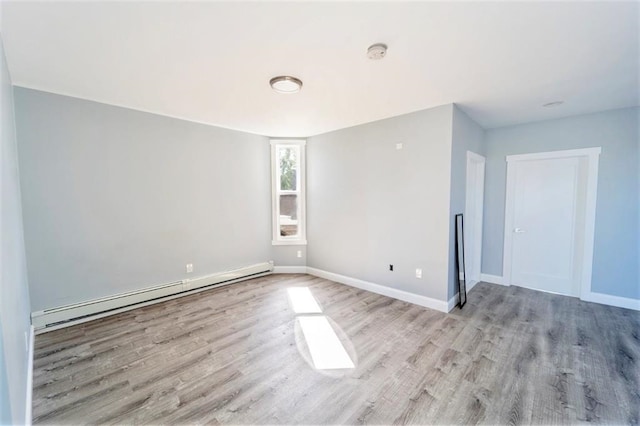 spare room with light wood-style floors, baseboards, and a baseboard radiator