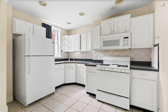 kitchen featuring white appliances, white cabinets, dark countertops, and backsplash