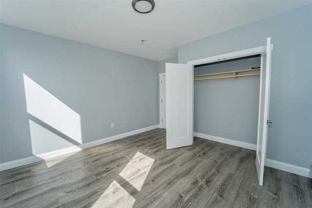 unfurnished bedroom with a closet, baseboards, and wood finished floors