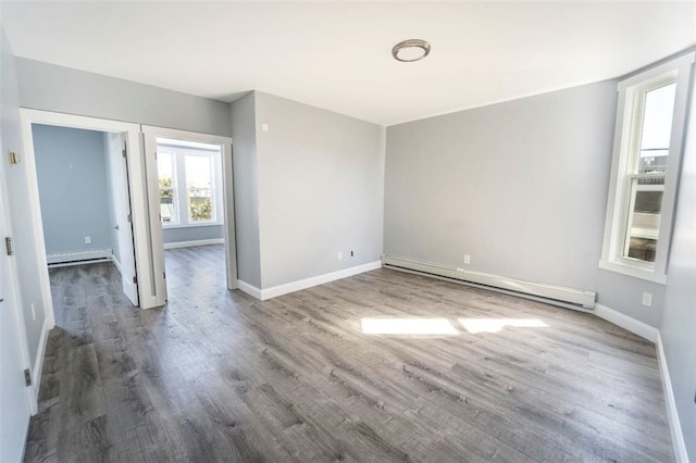 spare room featuring a baseboard radiator, baseboards, and wood finished floors