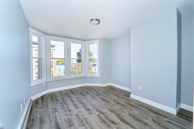 unfurnished room with wood finished floors, baseboards, and a baseboard radiator