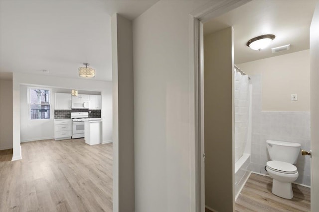 bathroom with shower / tub combo with curtain, toilet, tasteful backsplash, tile walls, and hardwood / wood-style floors