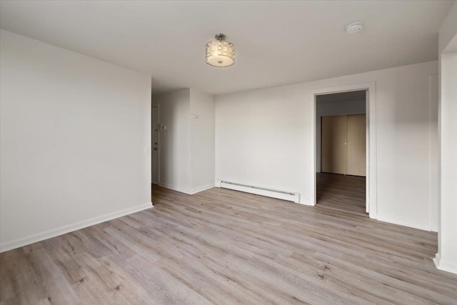 empty room featuring a baseboard heating unit and light hardwood / wood-style flooring