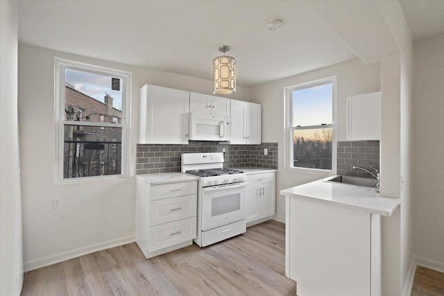 kitchen with sink, white appliances, backsplash, light hardwood / wood-style floors, and white cabinets