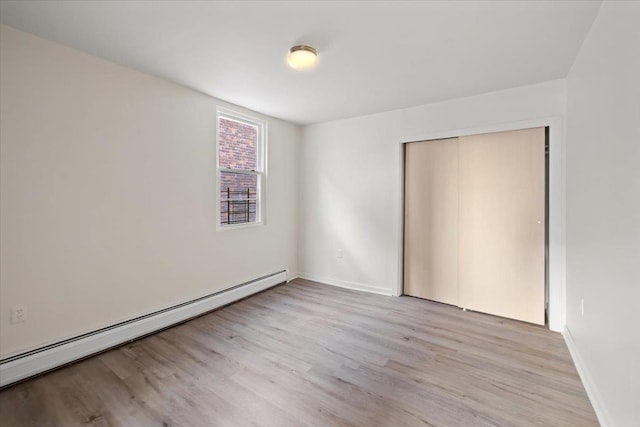 unfurnished room with a baseboard radiator and light wood-type flooring