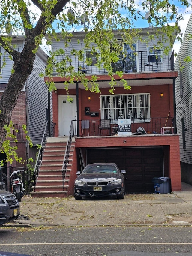 view of front facade with stairs, an attached garage, and a balcony