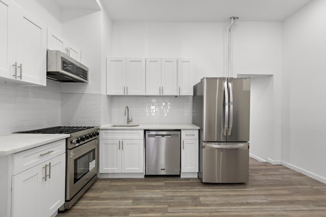 kitchen featuring light countertops, appliances with stainless steel finishes, wood finished floors, white cabinetry, and a sink