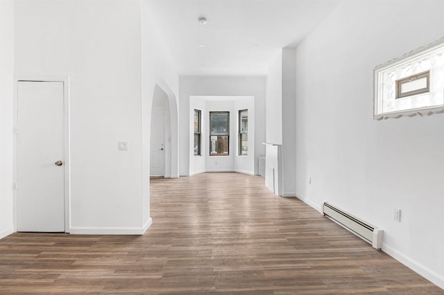 hall with a baseboard heating unit, arched walkways, baseboards, and wood finished floors