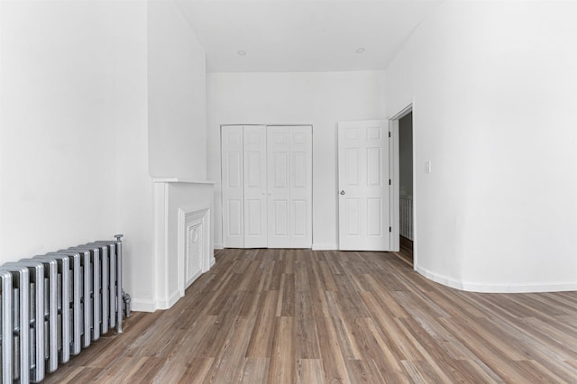 interior space with radiator heating unit, baseboards, and wood finished floors