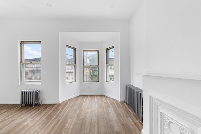 unfurnished living room featuring baseboards, radiator, and wood finished floors