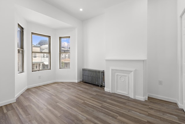 interior space featuring recessed lighting, baseboards, radiator, and wood finished floors