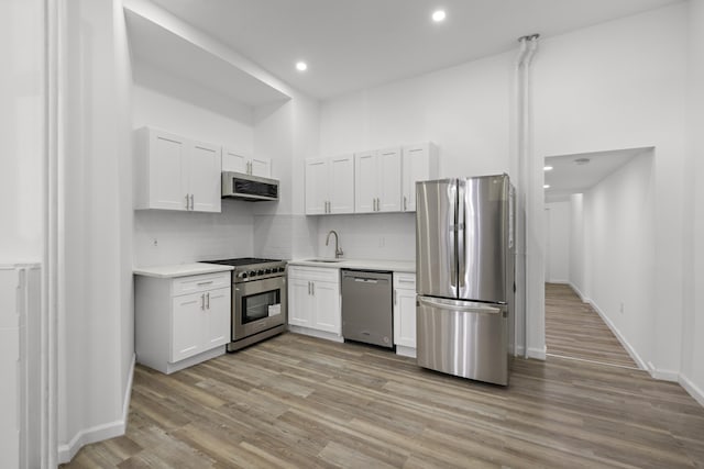 kitchen featuring a sink, white cabinetry, appliances with stainless steel finishes, light wood finished floors, and light countertops