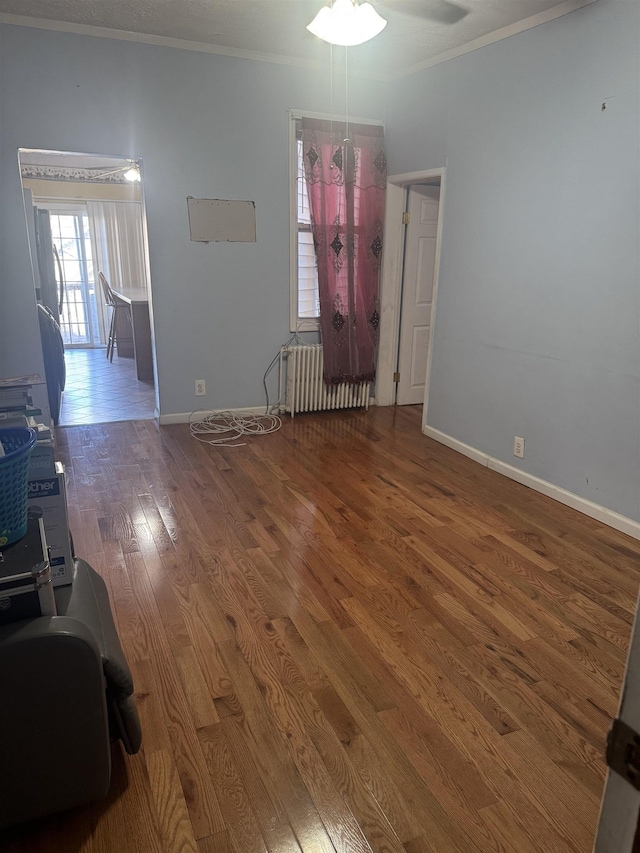 unfurnished room featuring crown molding, radiator heating unit, ceiling fan, and dark hardwood / wood-style floors