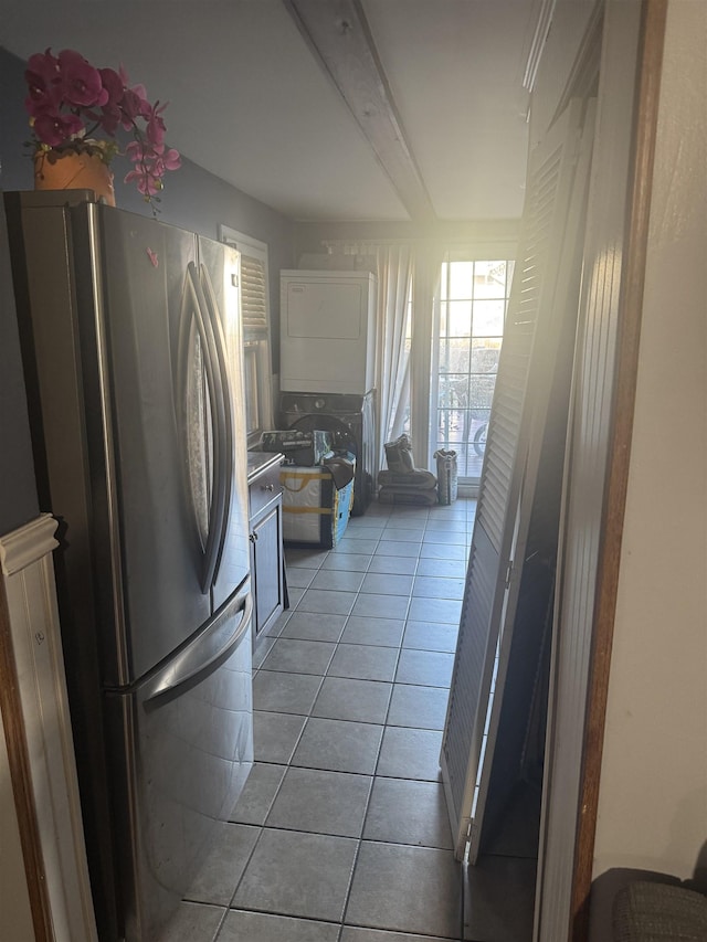 kitchen with beamed ceiling, stainless steel fridge, light tile patterned flooring, and stacked washer and dryer