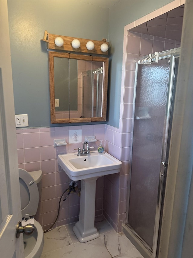 bathroom featuring a shower with shower door, tile walls, and toilet