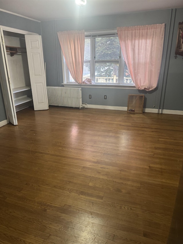 unfurnished bedroom featuring radiator heating unit, dark hardwood / wood-style flooring, and a closet