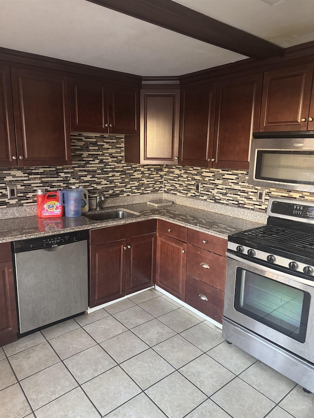 kitchen with decorative backsplash, appliances with stainless steel finishes, dark stone counters, and sink