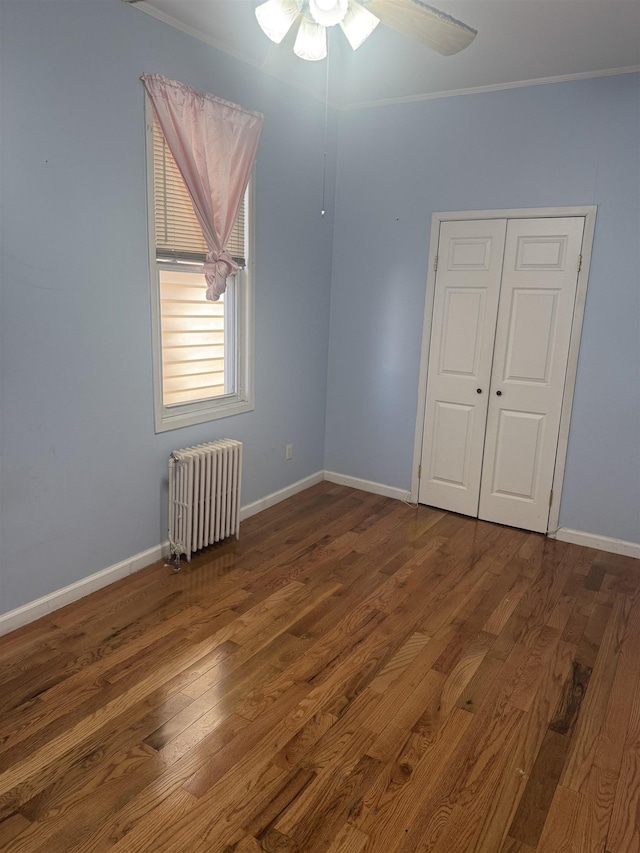 unfurnished room with ceiling fan, ornamental molding, dark wood-type flooring, and radiator