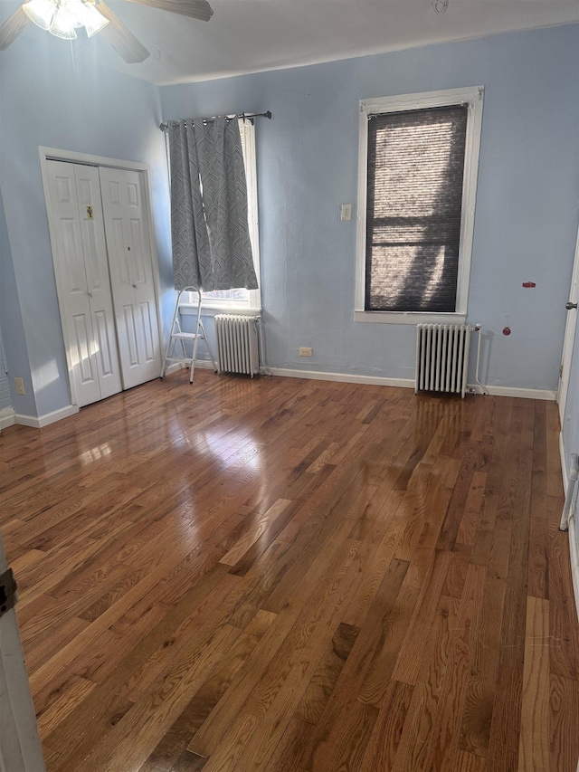 spare room featuring dark hardwood / wood-style floors, ceiling fan, and radiator