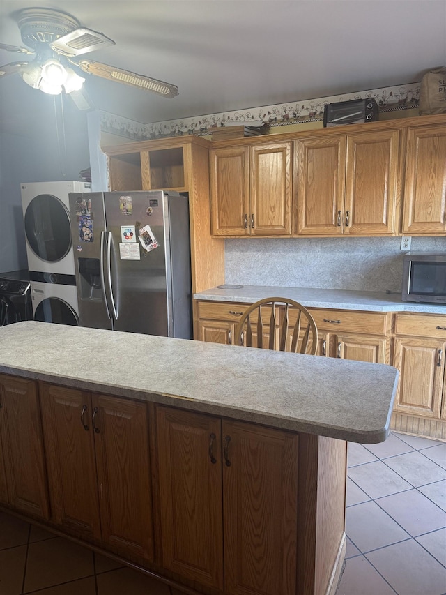 kitchen with ceiling fan, light tile patterned floors, stacked washer and clothes dryer, and appliances with stainless steel finishes