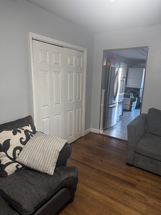 bedroom with a closet, stainless steel fridge, and dark hardwood / wood-style flooring