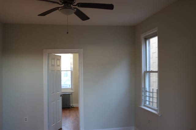 empty room with hardwood / wood-style flooring, radiator heating unit, and ceiling fan