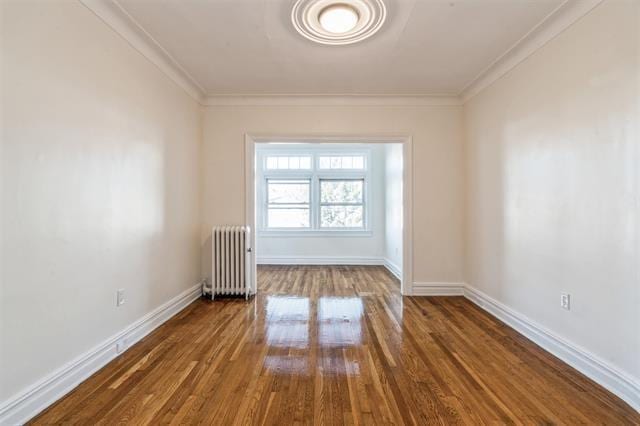 spare room with crown molding, radiator heating unit, and wood-type flooring