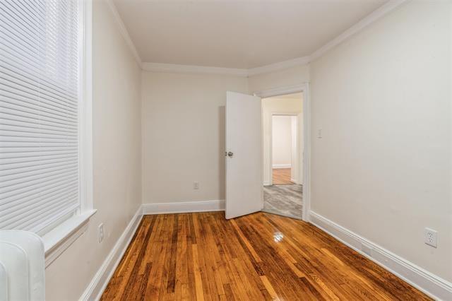 empty room featuring crown molding, radiator heating unit, and hardwood / wood-style flooring