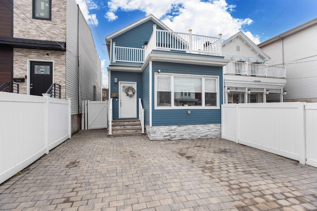 view of front of property with a patio, a gate, fence private yard, and a balcony