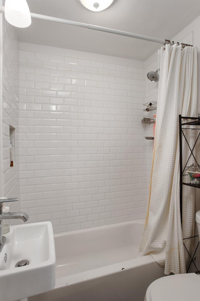 full bathroom featuring toilet, shower / bathtub combination with curtain, and a sink