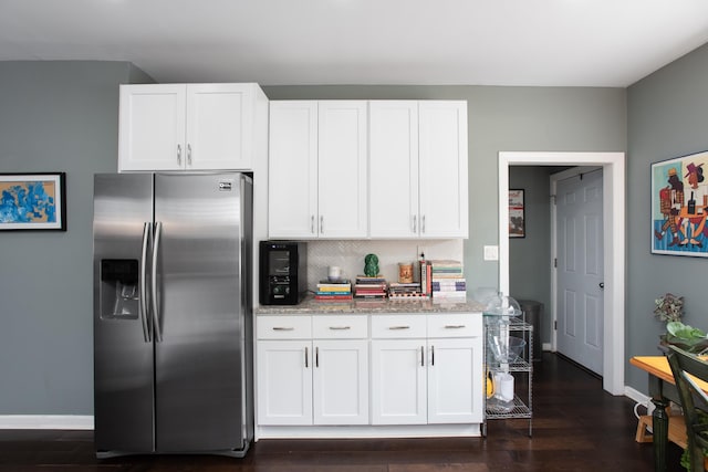 kitchen featuring tasteful backsplash, white cabinets, light stone counters, dark wood-type flooring, and stainless steel refrigerator with ice dispenser