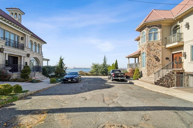 view of street with sidewalks, a water view, and curbs