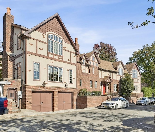 view of front facade with brick siding, a chimney, and stucco siding