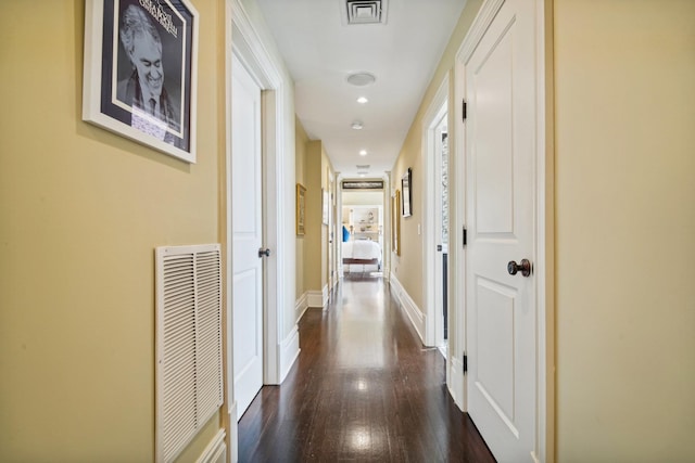 hall with dark wood-style floors, visible vents, and baseboards