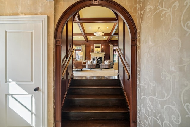 staircase featuring arched walkways, a fireplace, recessed lighting, coffered ceiling, and beamed ceiling