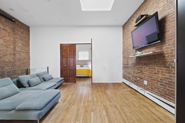 unfurnished living room featuring baseboards, brick wall, light wood-style flooring, a skylight, and baseboard heating