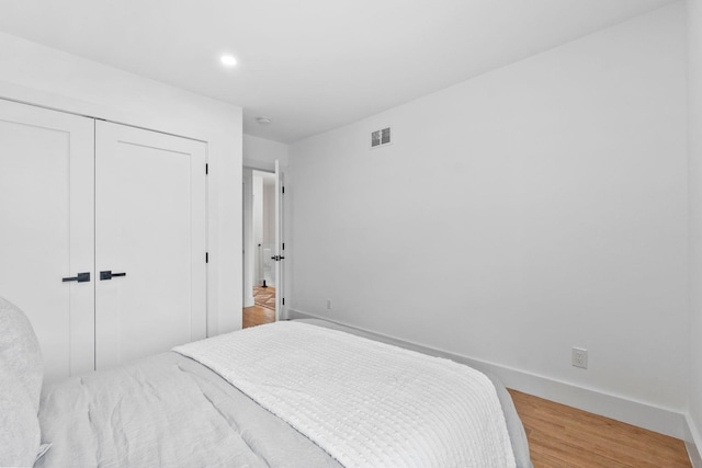 bedroom with recessed lighting, a closet, visible vents, wood finished floors, and baseboards