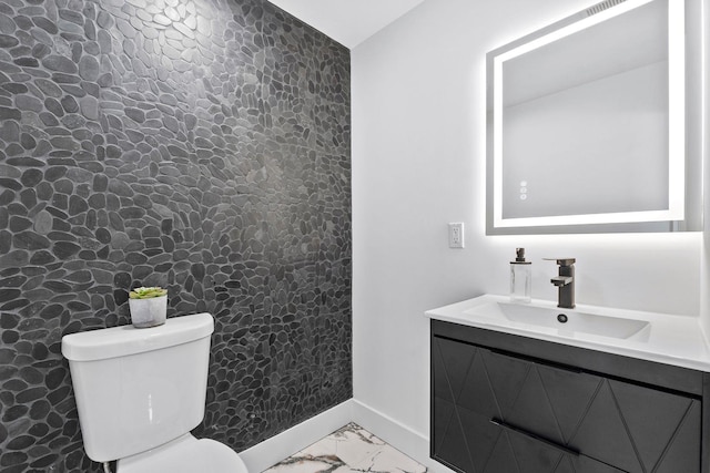 half bath featuring marble finish floor, vanity, toilet, and baseboards